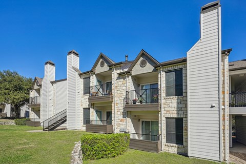 Row of our apartment buildings with balconies and a clear blue sky at On the Green apartments in Austin, TX